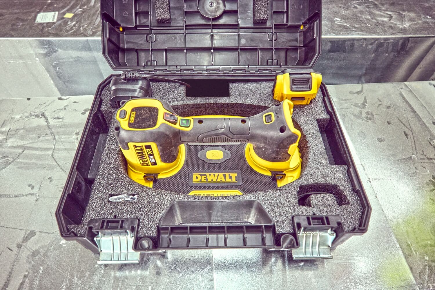 Herramienta DEWALT en estuche negro con espuma, accesorio y cierres de seguridad.