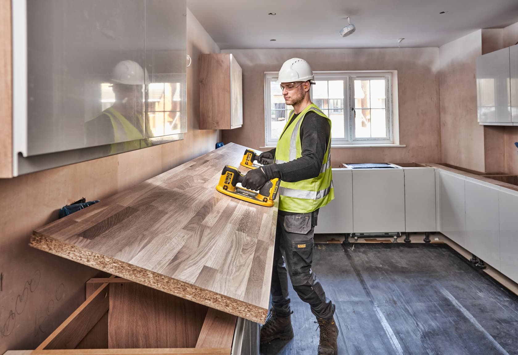 Trabajador usa la herramienta DEWALT DCE590 para instalar una encimera de madera en una cocina.
