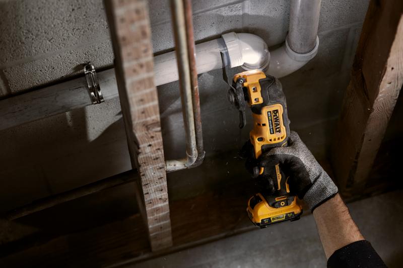 Persona corta un tubo con herramienta oscilante DEWALT inalámbrica junto a una pared de hormigón.