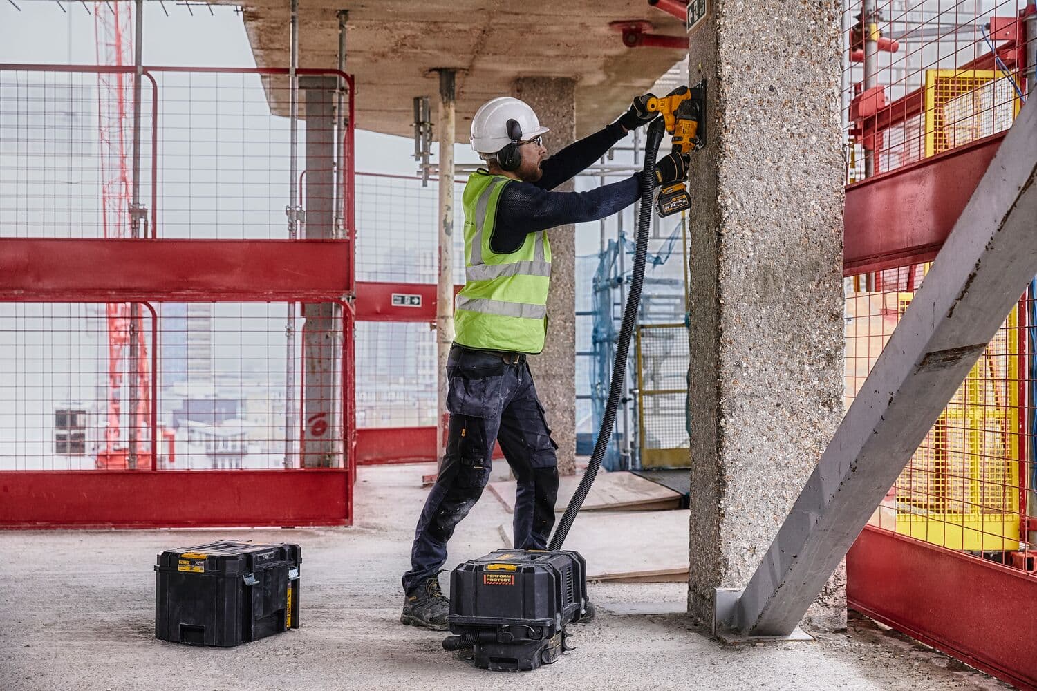 Un trabajador de la construcción con equipo de seguridad, incluido casco y chaleco reflectante, usa una herramienta