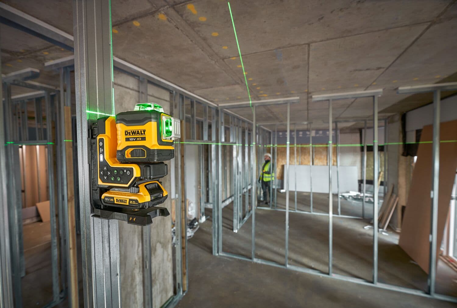 Nivel láser verde DEWALT montado en perfil metálico para alineación en edificio sin terminar.