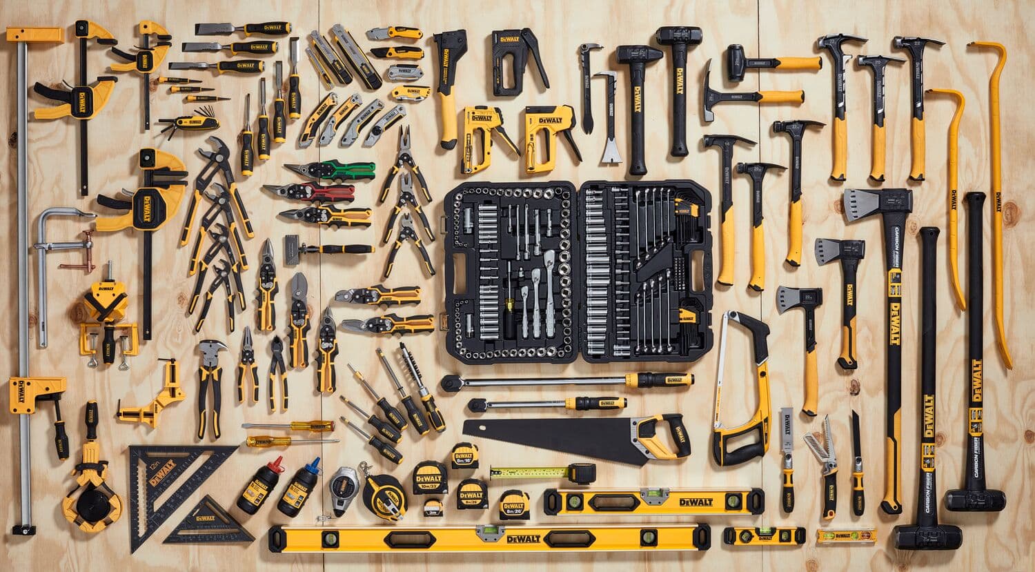 Herramientas manuales DEWALT y accesorios variados dispuestos sobre madera para fotografía.