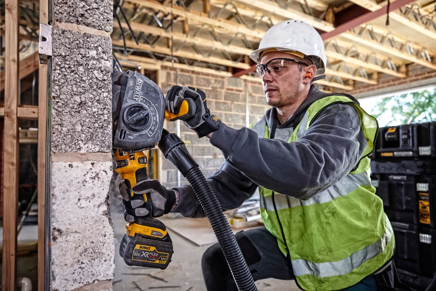 Trabajador usa DEWALT DCG200T2 en pared de concreto, con equipo de seguridad.